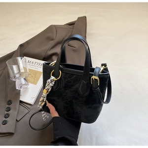 Detail of black patterned bucket bag with silk scarf and elegant gold hardware