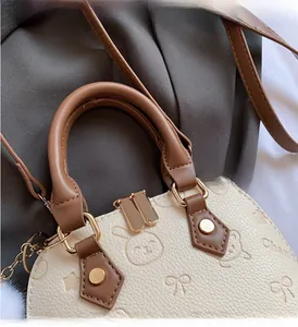 Close-up of cream shell handbag with brown handles and rabbit bear embossed patterns