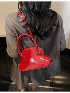Glossy bright red shell bag with top handles and silver hardware shown with a model