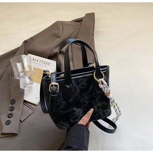Detail of black embossed bucket bag with galaxy pattern and woven rope accessory