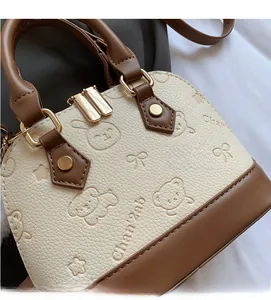 Close-up of shell crossbody bag showing embossed animal patterns and litchi texture