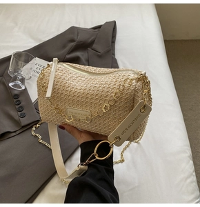 Detail of bohemian straw barrel bag featuring floral gold chain and white leather strap