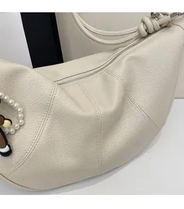 Detail of cream white pebbled leather hobo bag with zipper and pearl charm