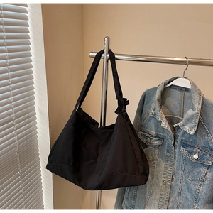 Detail of black tote bag with geometric stitching and bow charm on a hanger