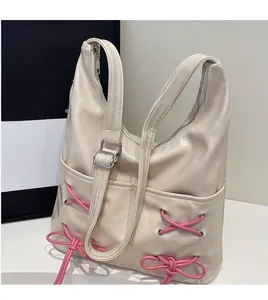Detail of cream leather tote with pink ribbon bows and smooth adjustable long shoulder strap