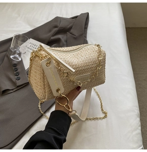 Detail of bohemian straw bag with floral chain link strap and woven texture on plain background