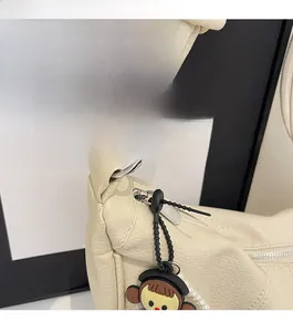 Detail of creamy white leather crossbody bag with silver hardware and knotted strap