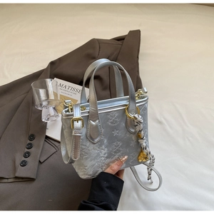 Detail of silver embossed bucket bag with gold hardware and woven rope pendant charm