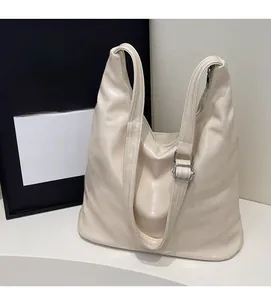 Close-up of cream tote bag featuring textured faux leather and silver metal buckles