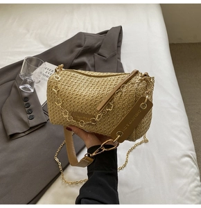 Macro shot of bohemian cylinder straw bag with golden chain and zip closure detail