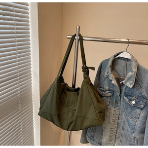 Close-up of olive green tote bag featuring geometric pleated texture and bow strap details