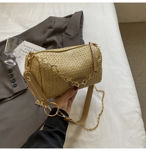 Detailed macro shot of bohemian straw barrel bag with floral chain and leather strap