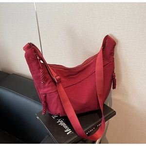 Macro detail of red nylon dumpling bag with woven zipper pull on minimalist books