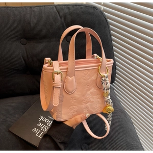 Detailed shot of pink star-embossed PU leather bucket bag with golden puppy charm