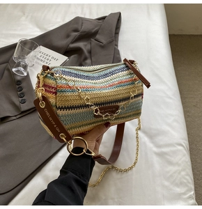 Detail of colorful woven straw barrel bag with floral chain and brown leather strap