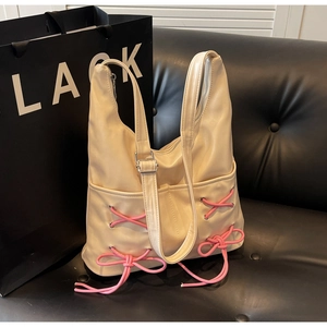 Detail of beige bucket bag featuring pink ribbon crossover laces and bow decoration