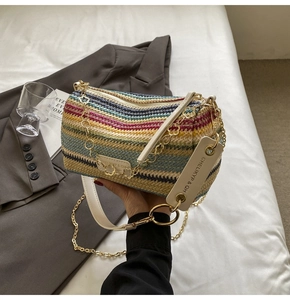 Detail of colorful rainbow woven barrel bag with gold chain and white leather strap