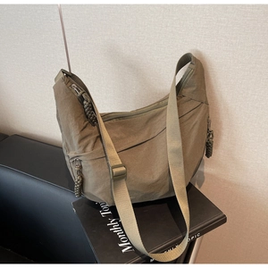 Detail of army green nylon dumpling bag with woven zipper pulls and multiple compartments