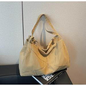 Detail of khaki tote bag with knot decor and textured fabric on a leather sofa