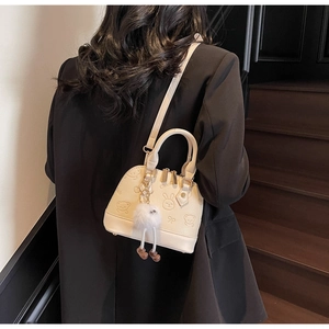 Detail of cream shell bag with embossed cartoon bears and plush charm on black stairs