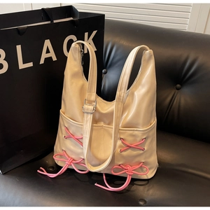 Detail of cream PU leather bucket bag featuring pink bow accents and front pocket on sofa