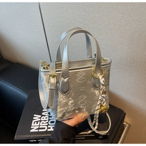 Detailed macro view of the silver embossed star pattern and lion head charm on handbag