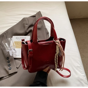 Dettaglio della borsa a secchiello in pelle lucida rosso scuro con logo XICH XICH inciso