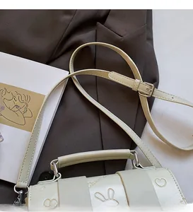 Detail of cream-white leather pillow bag with embossed heart and rabbit ear textures