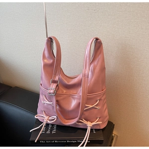 Detail of pink bow-tied bucket bag showing side pockets and silver adjustable buckle