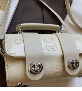 Detailed view of cream pillow bag with rabbit embossing and silver metal twist lock
