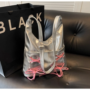 Detail of silver bucket bag featuring pink ballet-core ribbon and bow on leather sofa