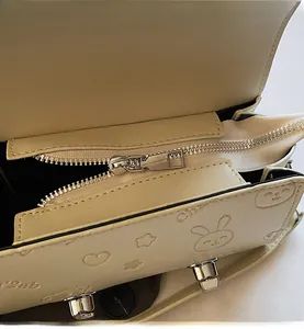 Detailed close-up of smooth metal zipper and cartoon embossed leather texture on bag