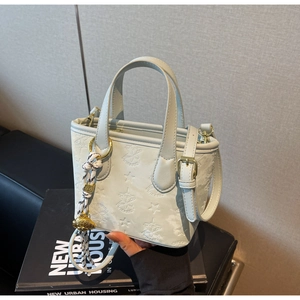Close-up of light blue leather bucket bag with embossed star patterns and woven pendant