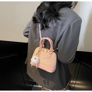 Detailed back view of pink shell bag with cartoon dog print and plush monster charm