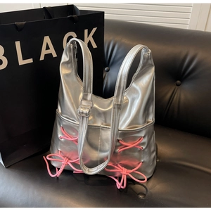 Close-up of silver Y2K metallic bucket bag featuring pink lace-up bow and metal buckles