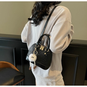 Detail of black shell bag with bear embossing and a plush charm shown from a side view