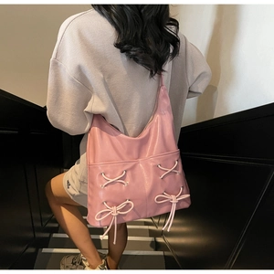 Close-up of pink shiny PU leather tote bag featuring metal eyelets and decorative bow tie
