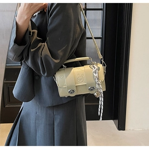 Detail view of cream crossbody bag featuring rabbit embossing and silk scarf handle wrap