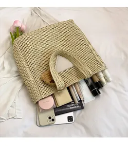 Vue à plat d'un sac cabas en paille tressée montrant l'intérieur spacieux et accessoires
