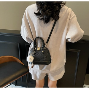 Detail of black shell-shaped handbag with cute bunny relief and plush charm