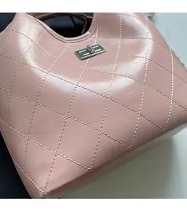 Gros plan du sac seau rose matelassé montrant la texture du cuir et le fermoir rotatif