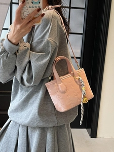Chic pink patent leather bucket bag with embossed star patterns and scarf detail