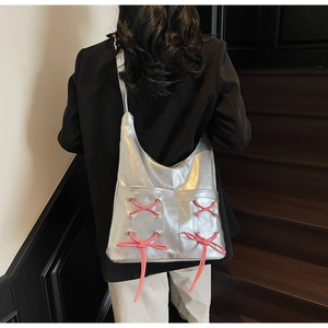 Detail of silver metallic tote bag featuring pink lace-up crisscross decorative ribbons