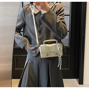Detail of cream crossbody bag featuring embossed rabbit pattern and silver metal clasps