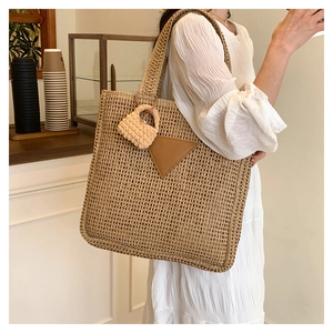 Détail du cabas en paille tressée avec patch triangle en cuir et breloque en maille
