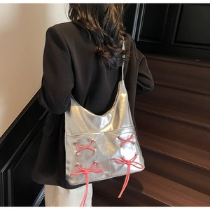 Detail of silver metallic tote bag featuring pink lace-up bows and smooth PU texture