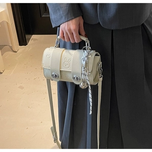 Detail of cream Boston bag featuring embossed rabbit patterns and a plaid ribbon handle