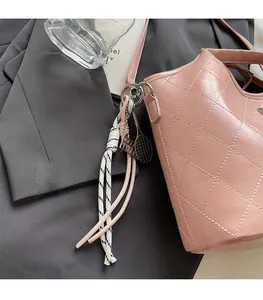 Détail d'un sac seau rose en cuir matelassé avec un charm décoratif de raquette de tennis