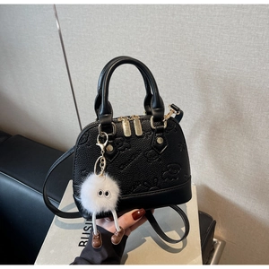 Detail of black shell bag featuring embossed bear patterns and a cute plush charm