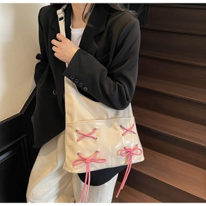Detail of cream leather bucket bag with pink bow accents and large capacity design